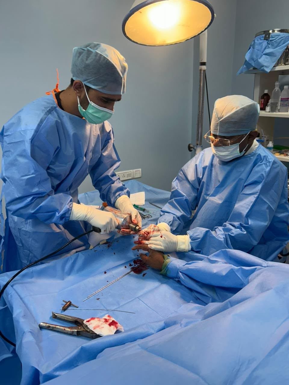 Orthopaedic surgeons fixing a hand fracture with a power drill